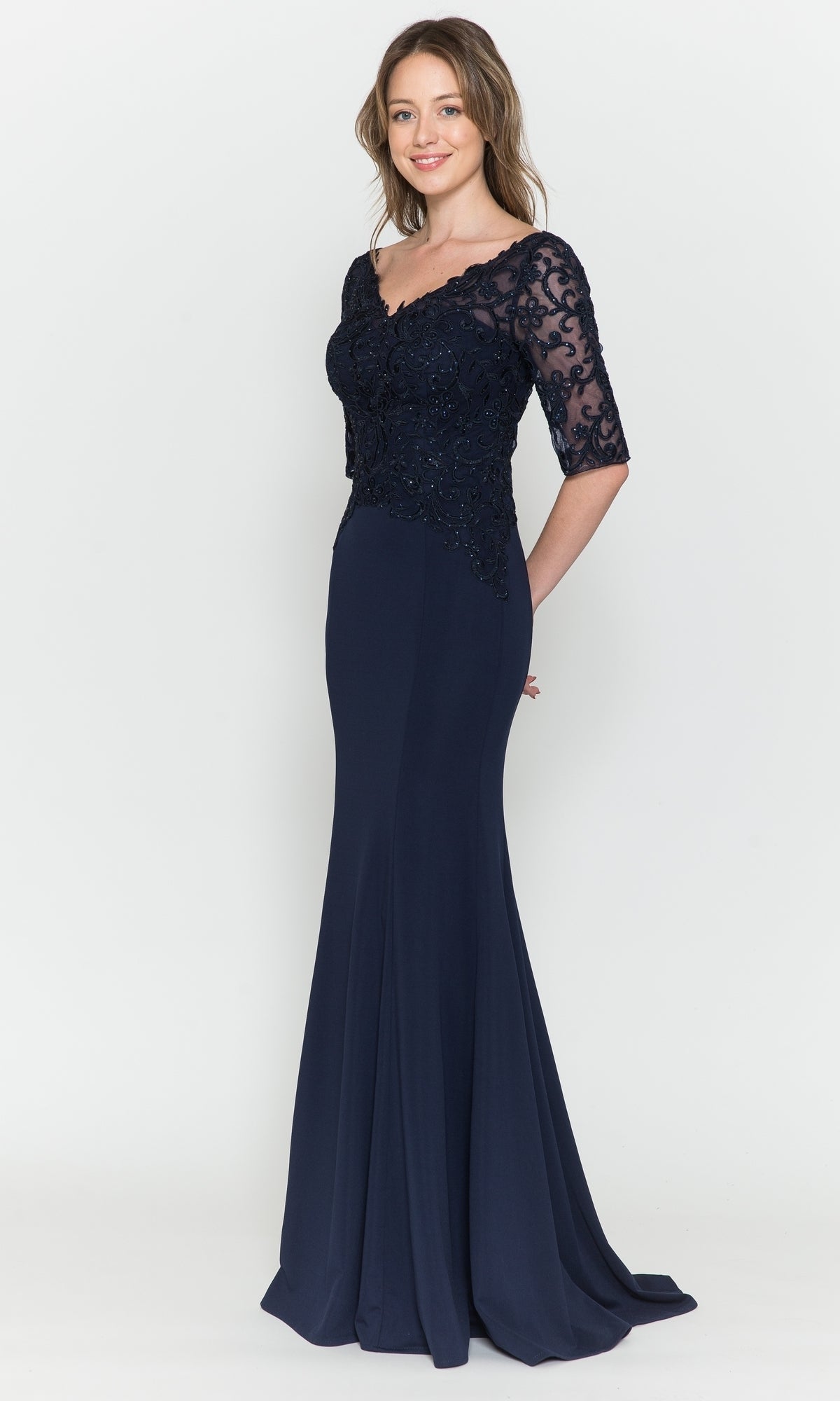 A woman poses against a plain white background in the Embroidered Sheer-Sleeved Formal Prom Dress 8560, a navy floor-length gown featuring lace detailing on the bodice and sheer sleeves.